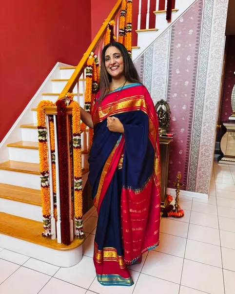 A navy saree with a red and gold border, styled at home